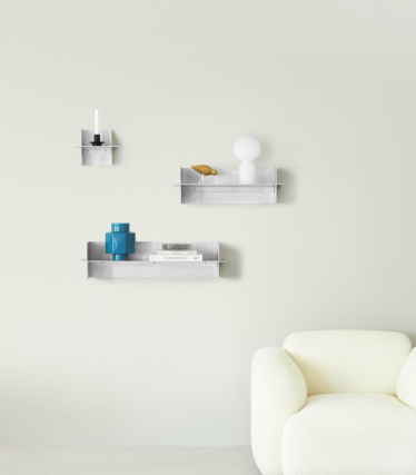 Estantes de pared transparentes Normann Copenhagen con accesorios decorativos en un espacio minimalista.