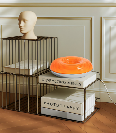 Moderna lámpara de mesa Lindby en naranja vibrante sobre un sistema de estanterías decorativo.