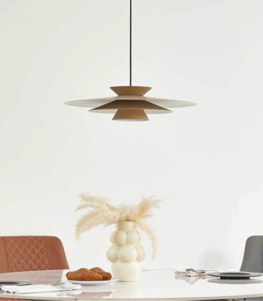 Lámpara colgante moderna sobre mesa de comedor con tonos naturales cálidos y diseño atemporal.