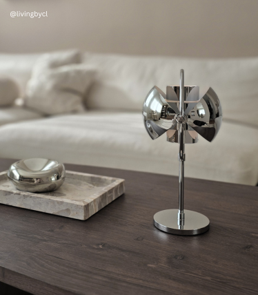 Ligera lámpara colgante sobre sillones bajos en una habitación tranquila y minimalista.