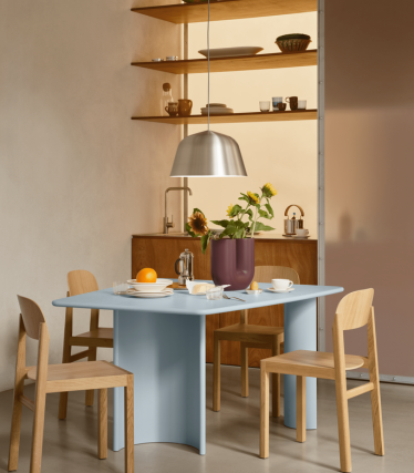 Comedor minimalista con lámpara colgante, estantes de madera y mesa puesta.