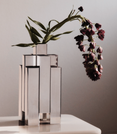 Jarrón escultural de acero inoxidable pulido de Ferm Living con flores rojo oscuro