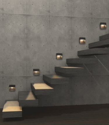 Apliques cuadrados oscuros acompañan una escalera de hormigón e iluminan los peldaños.